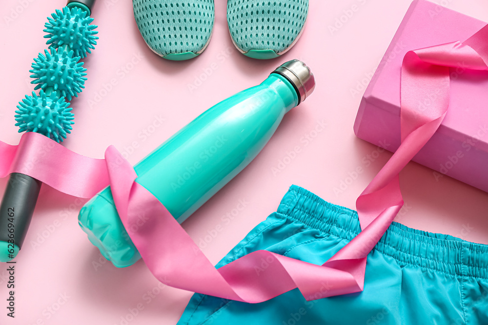 Composition with sports equipment, bottle of water and clothes on pink background