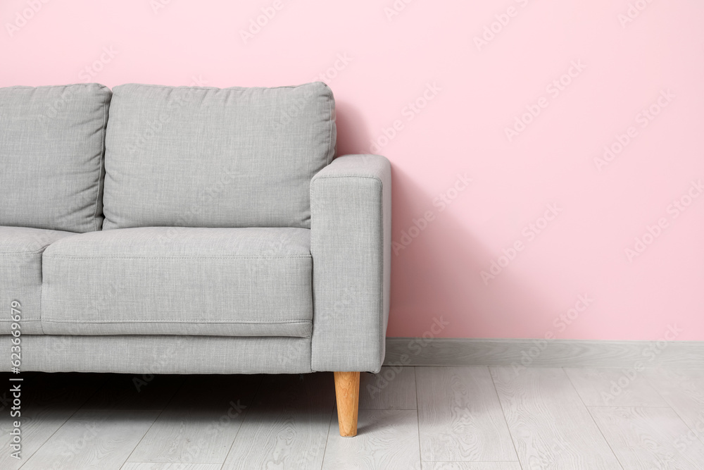 Cozy grey sofa near pink wall