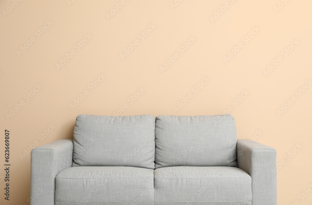 Cozy grey sofa near beige wall