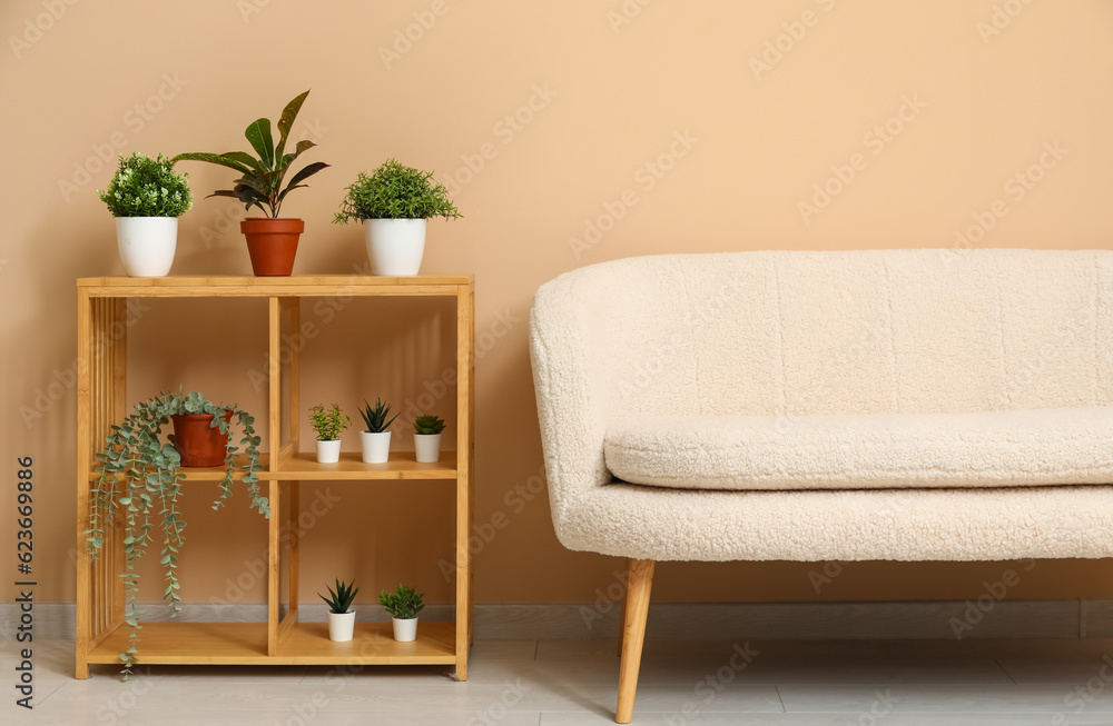 Modern living room interior with cozy white sofa, shelving unit and plants