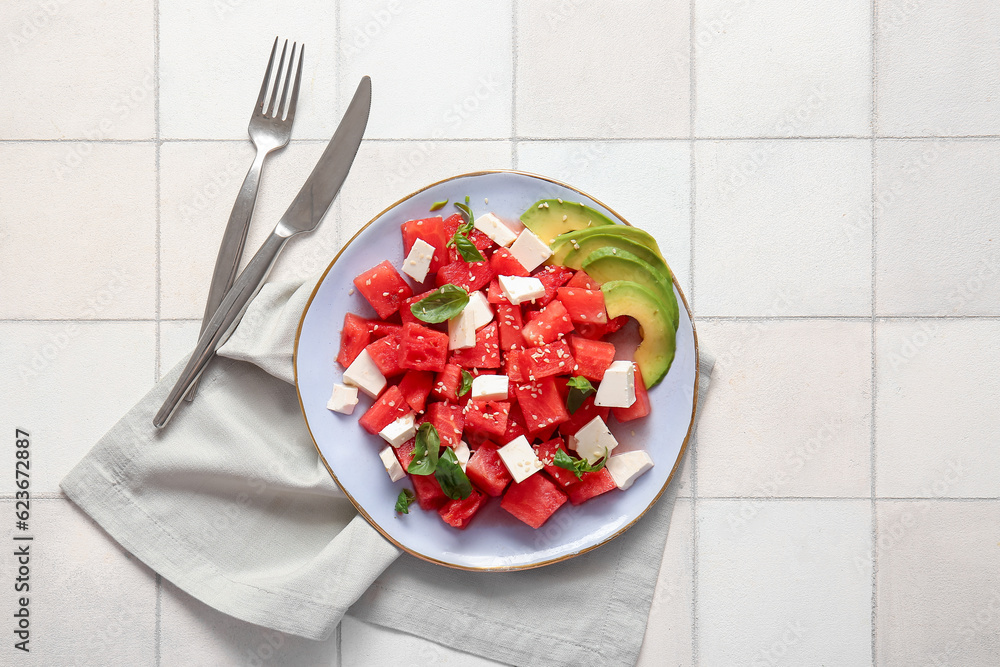 Plate of tasty watermelon salad on white tile background