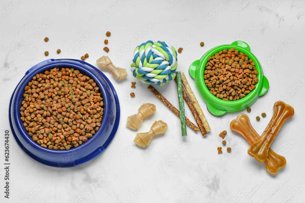 Composition with different dog food and toy ball on light background