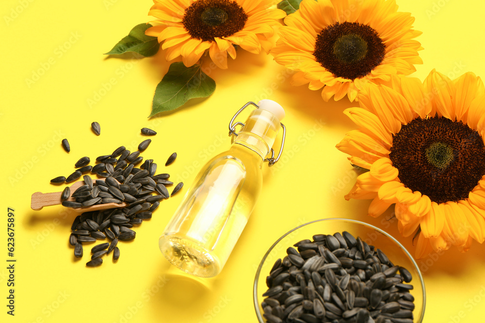 Sunflowers, seeds and bottle of oil on yellow background