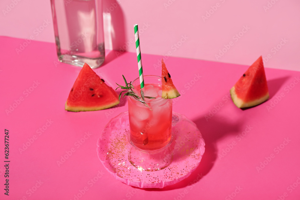 Glass of tasty watermelon cocktail with mini inflatable ring on pink table near wall