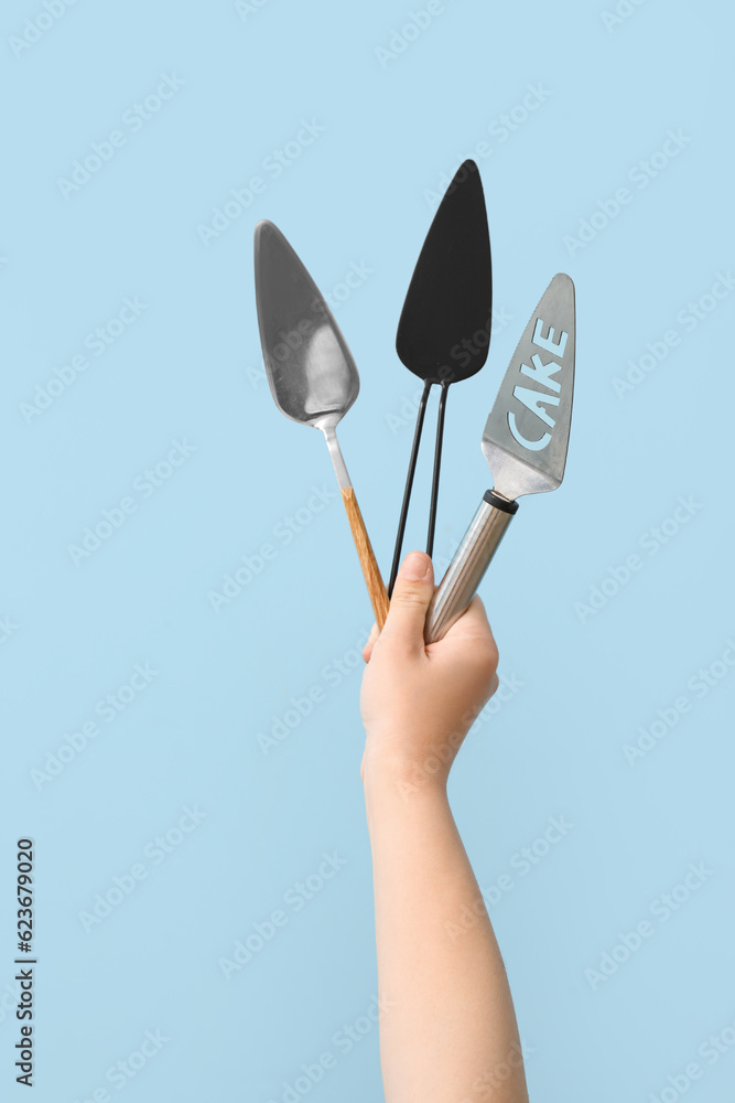 Female hand with spatulas on blue background