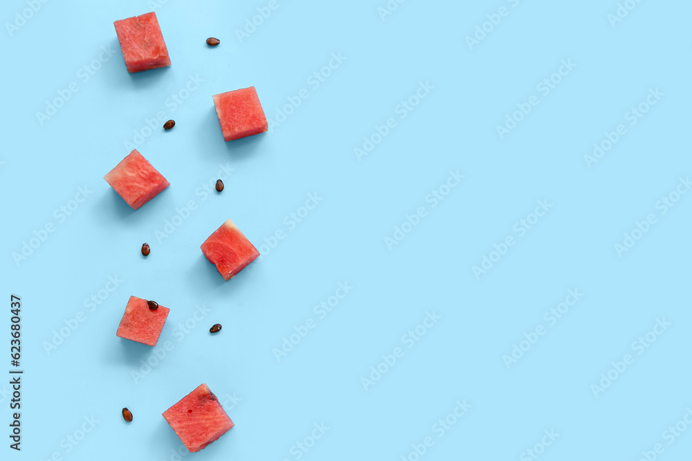 Pieces of fresh watermelon and seeds on blue background