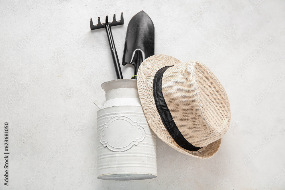 Different gardening tools and hat on light background