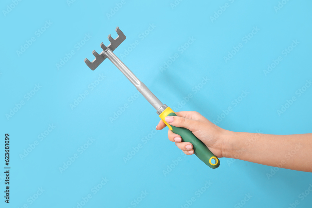 Woman with gardening rake on blue background