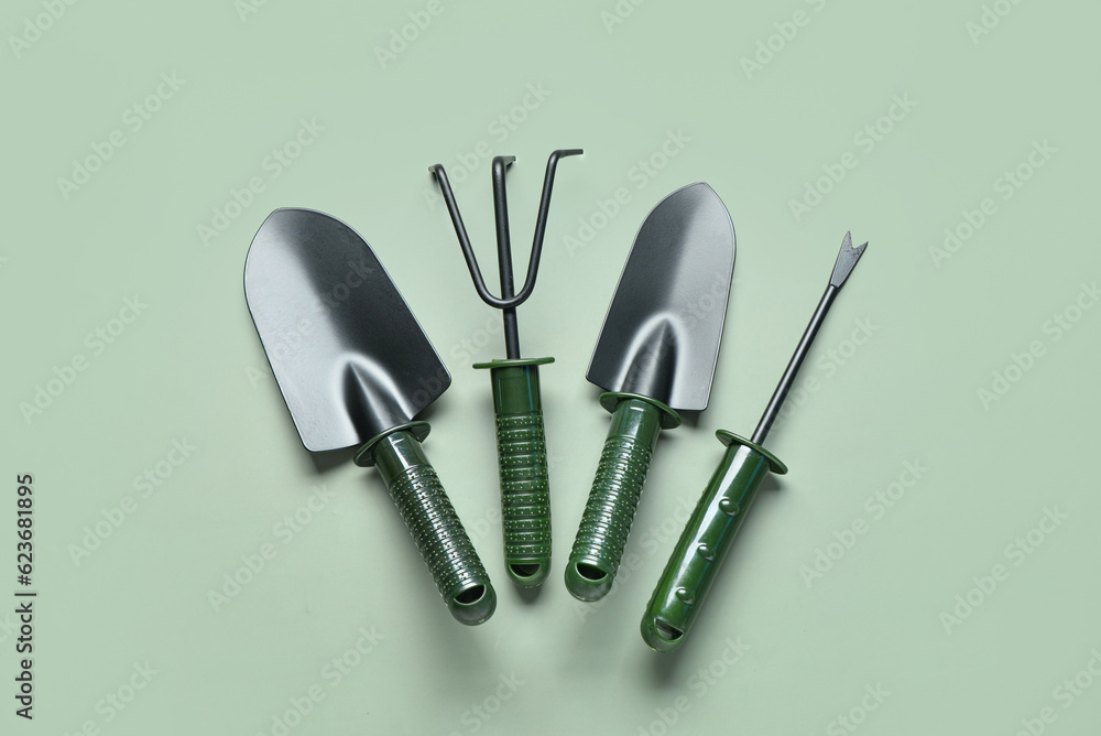 Gardening rake, shovels and weeder on green background