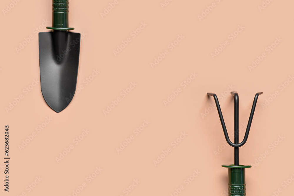 Gardening rake and shovel on beige background