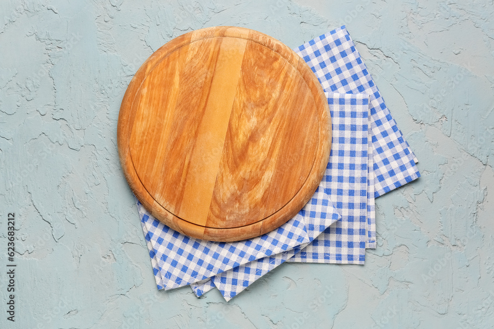 Wooden kitchen board and clean napkins on color background