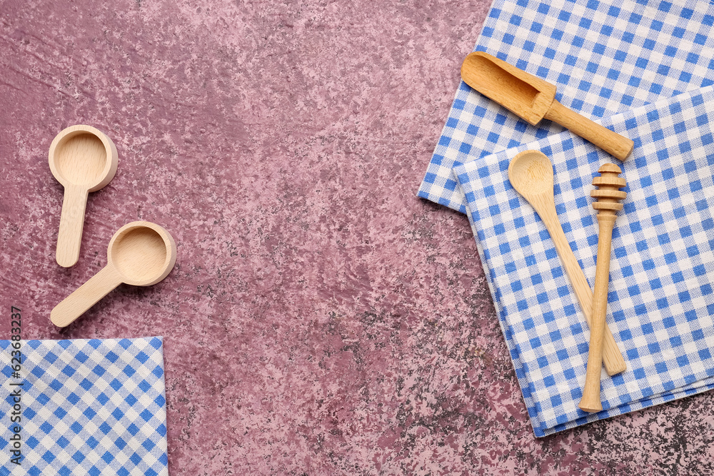 Set of wooden kitchen utensils and clean napkins on color background