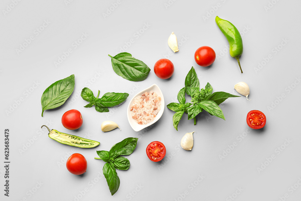 Fresh basil, cherry tomatoes and garlic on grey background