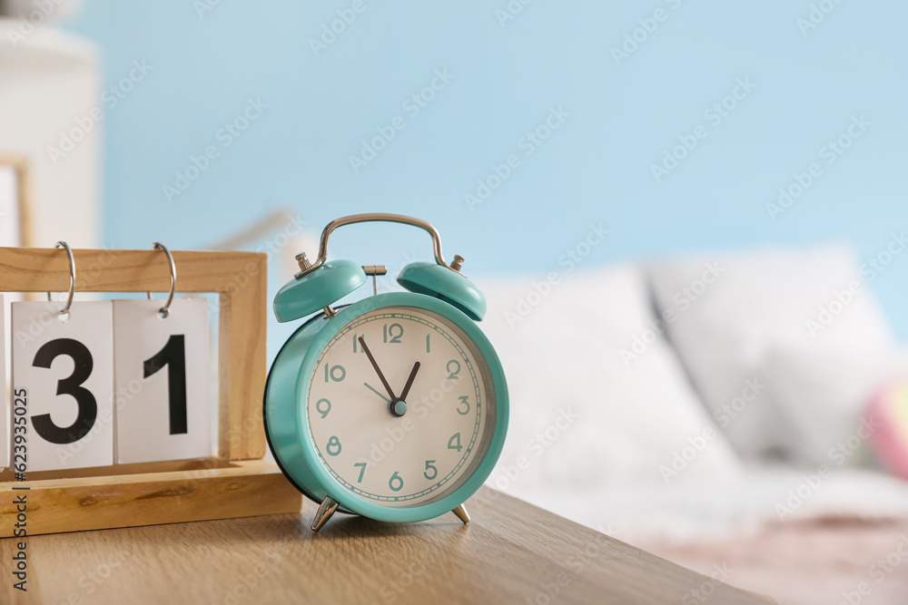 Vintage alarm clock with calendar on table in bedroom, closeup