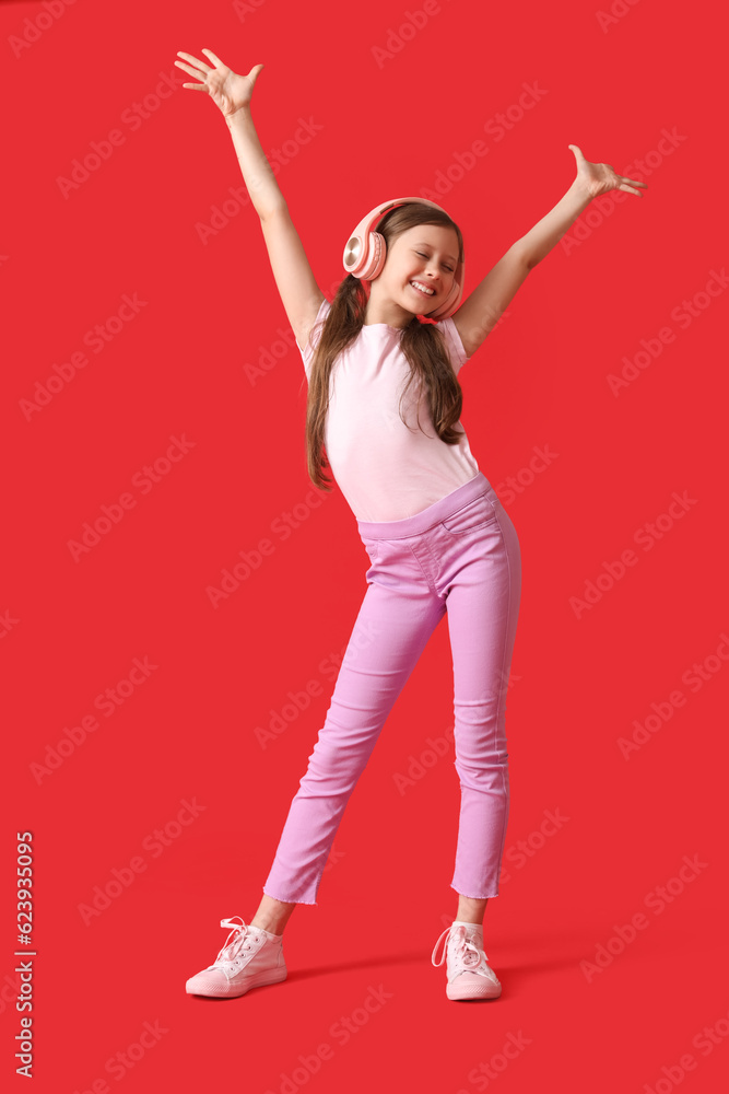 Little girl in headphones dancing on red background