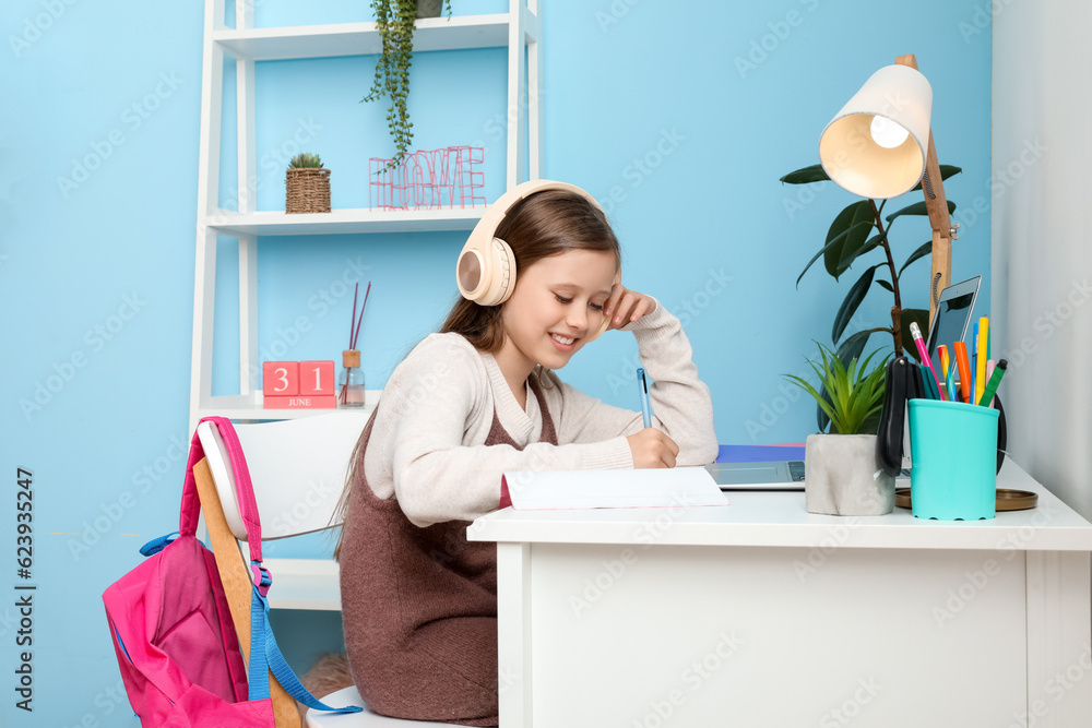 Little girl in headphones studying at home