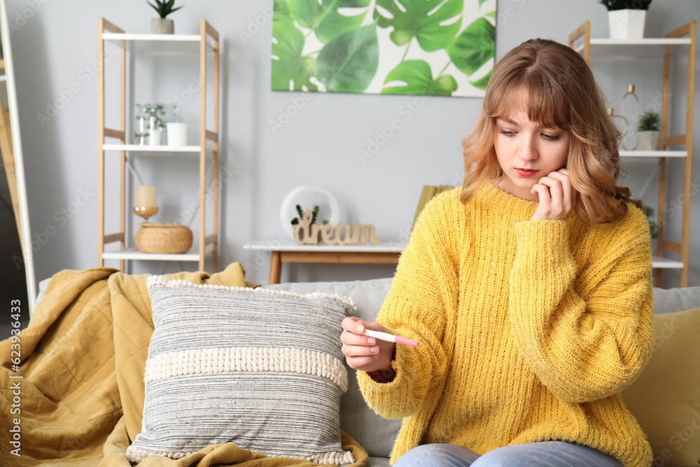 Sad young woman with pregnancy test at home