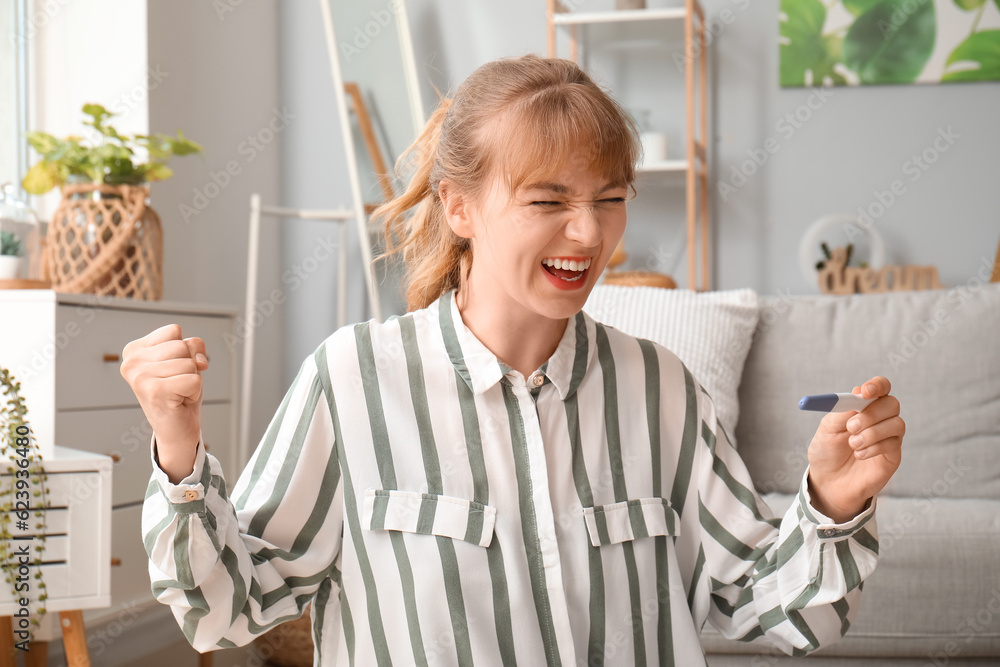 Happy young woman with pregnancy test at home