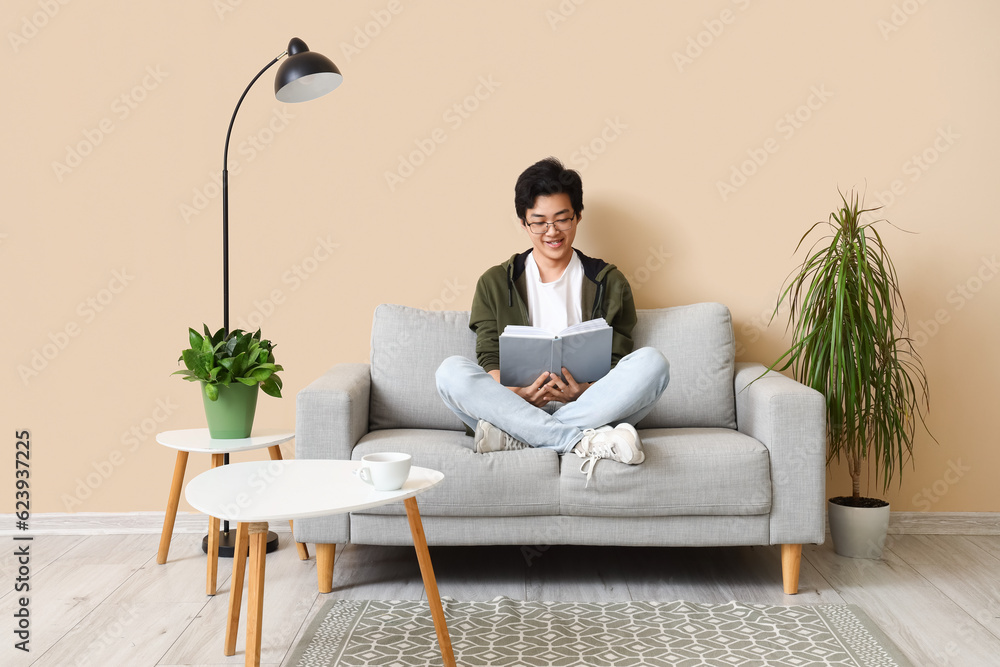 Young Asian man reading book on his day off at home