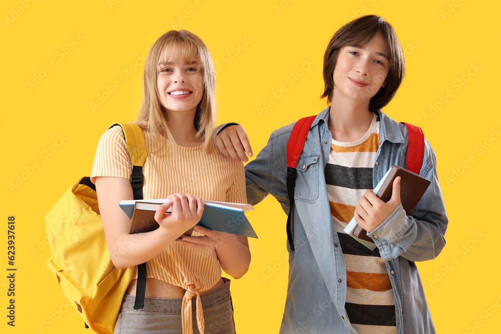 Teenage students with books on yellow background