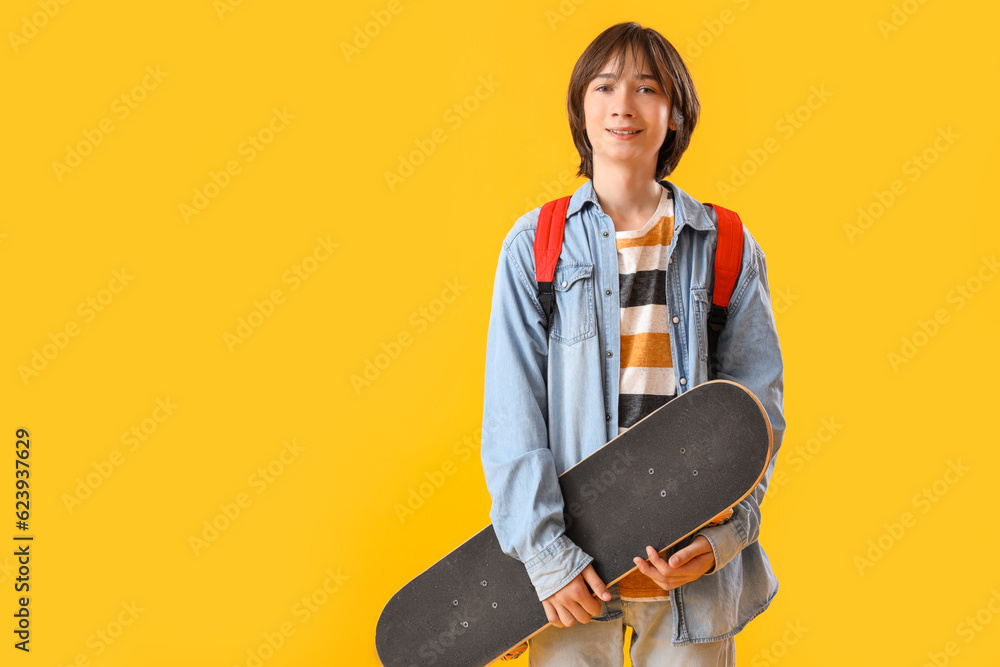 Male student with skateboard on yellow background