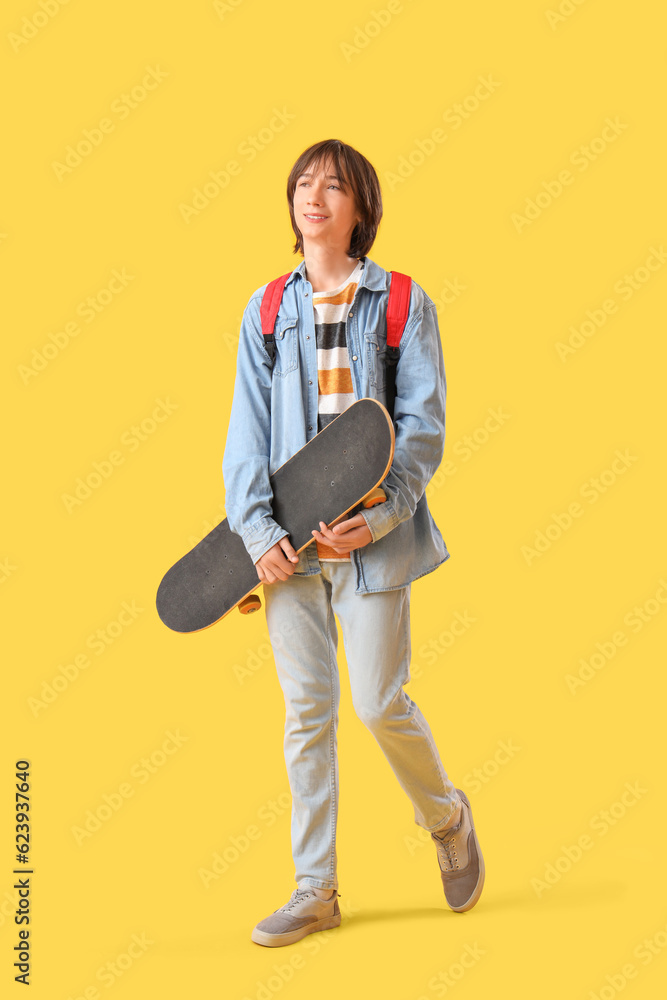 Male student with skateboard on yellow background