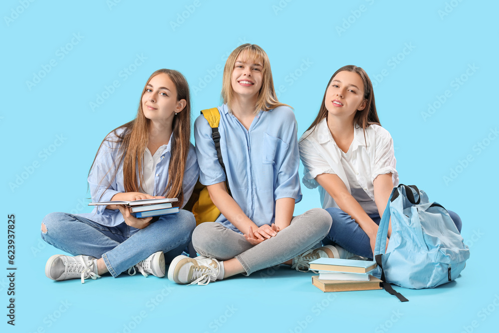 Female students sitting on blue background