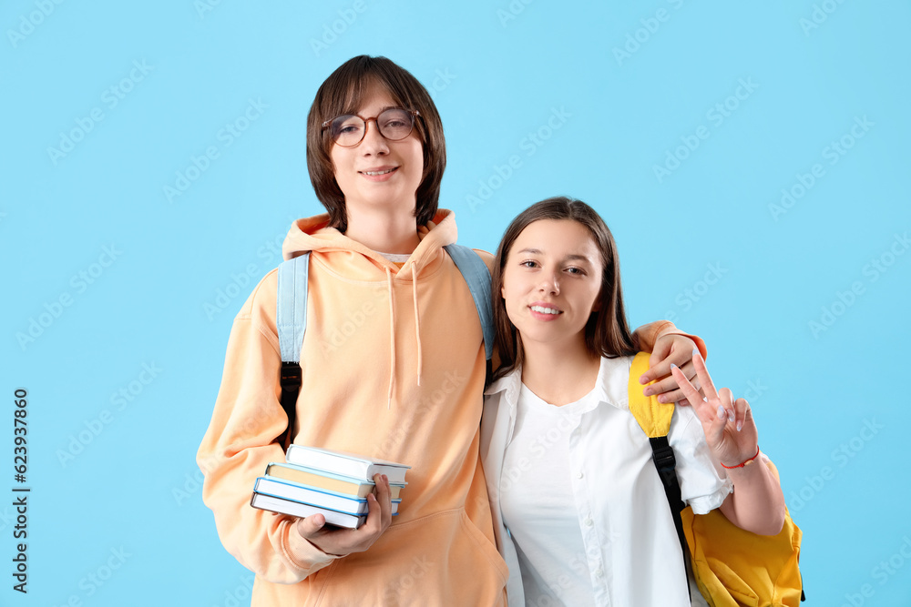 Couple of teenage students hugging on blue background