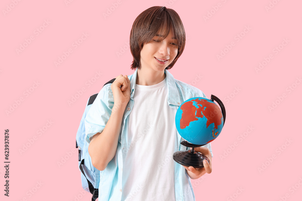 Male student with globe on pink background