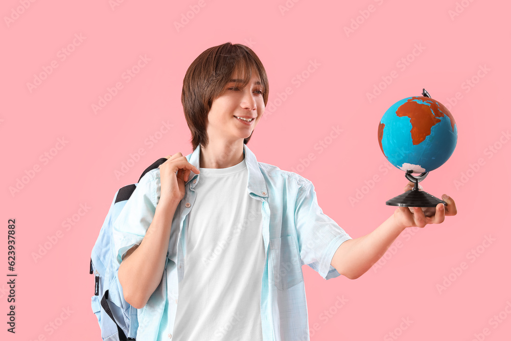 Male student with globe on pink background