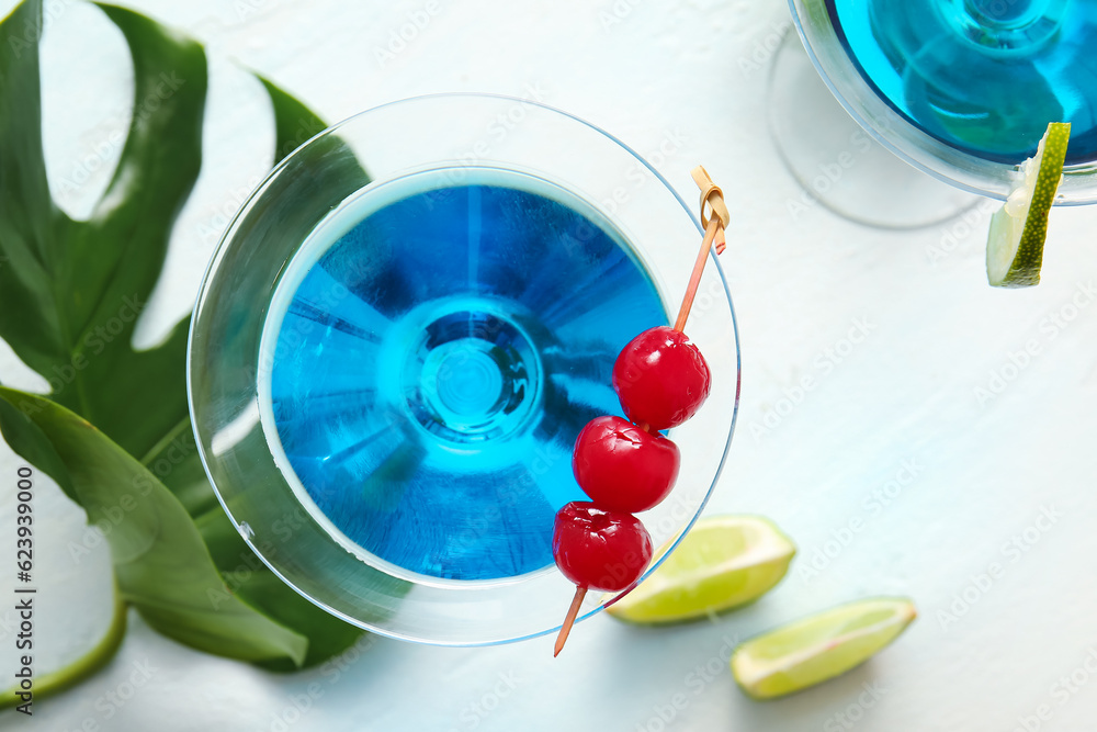 Glasses of tasty cocktail with maraschino cherries on light background