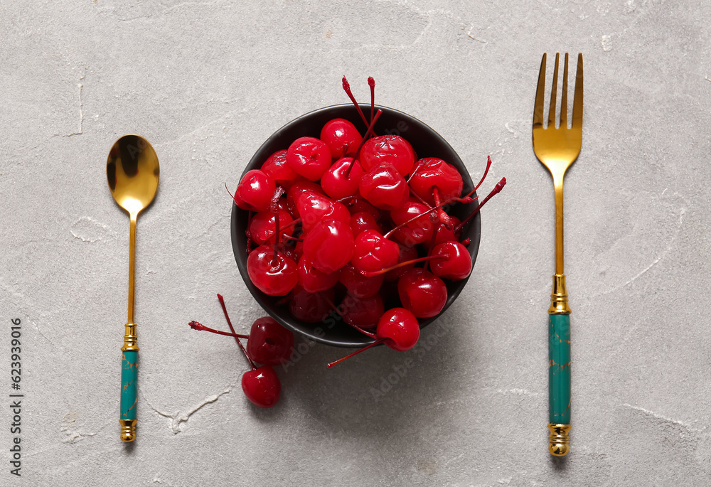 Bowl of tasty maraschino cherries on grey background