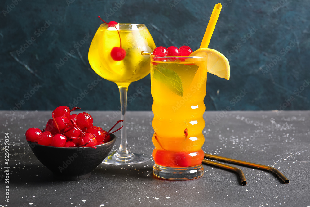 Glasses of tasty cocktail with maraschino cherries on grey background