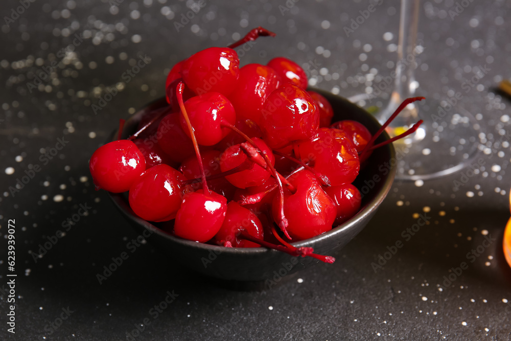 Bowl of tasty maraschino cherries on grey background