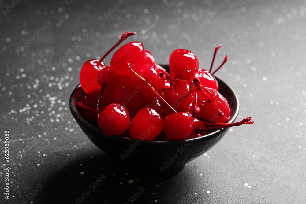 Bowl of tasty maraschino cherries on grey background