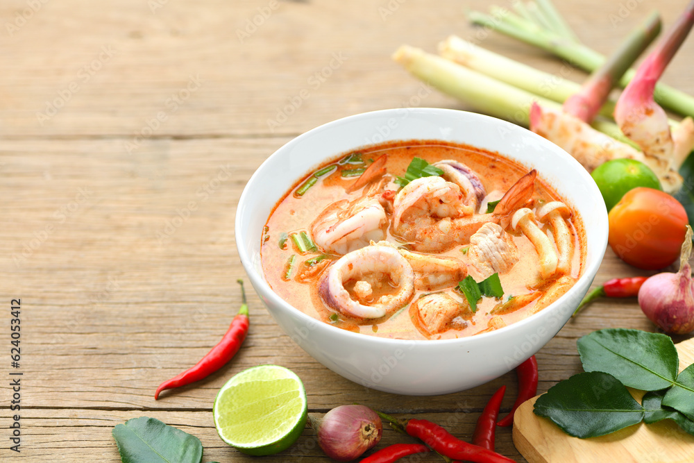 Tom yum soup with ingredient seasoning on wooden table.