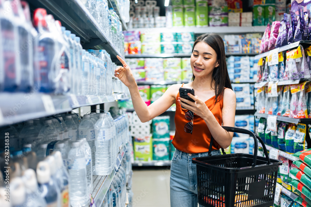 Asian young beautiful woman holding grocery basket walk in supermarket. 