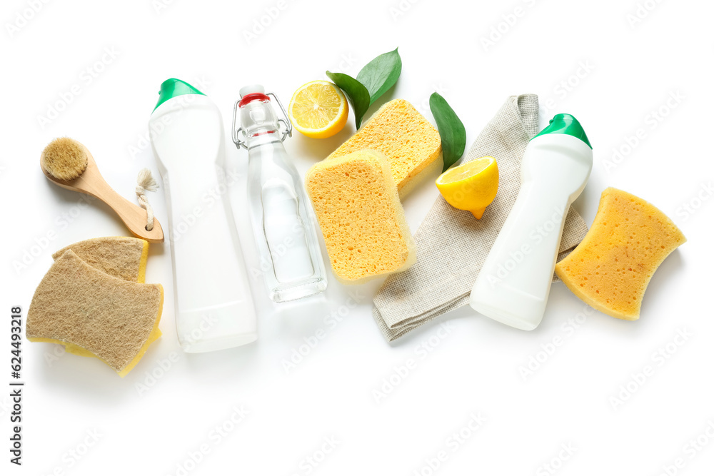 Bottles of vinegar, detergents, lemons, brush and sponges on white background