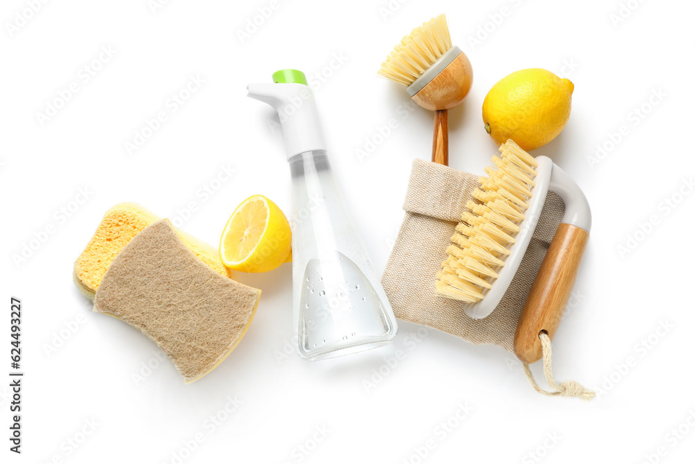 Bottle of vinegar, brushes, sponges and lemons on white background