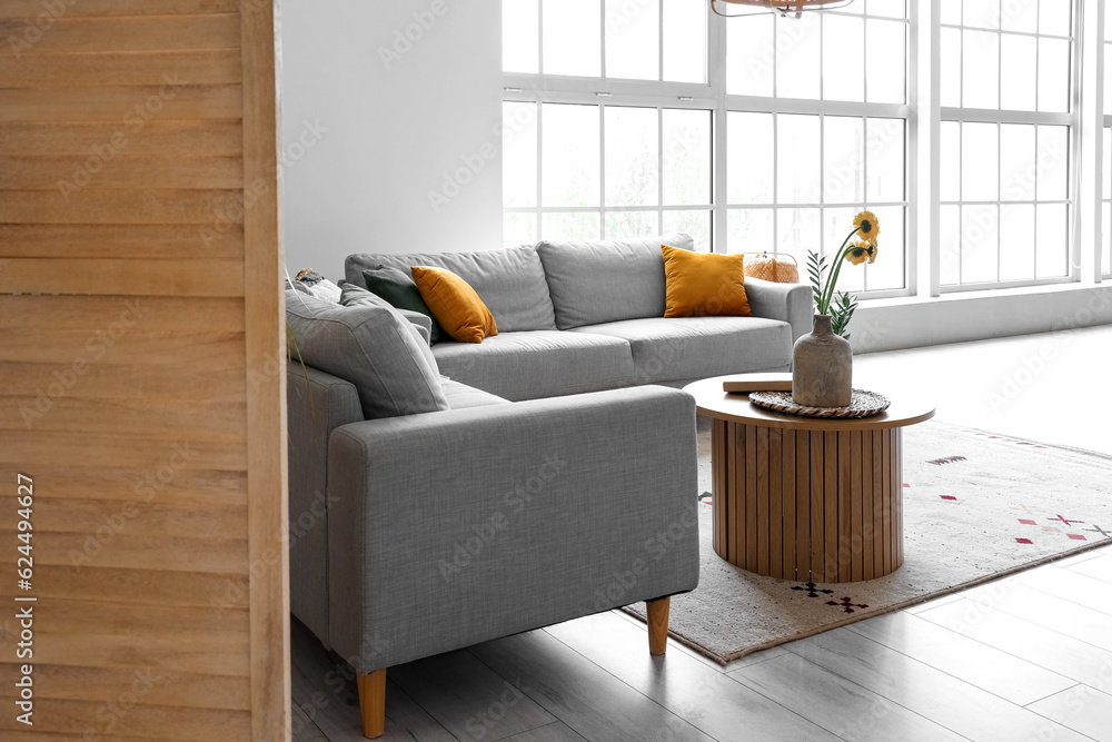 Interior of living room with sofas, coffee table and big window, view from behind the folding screen