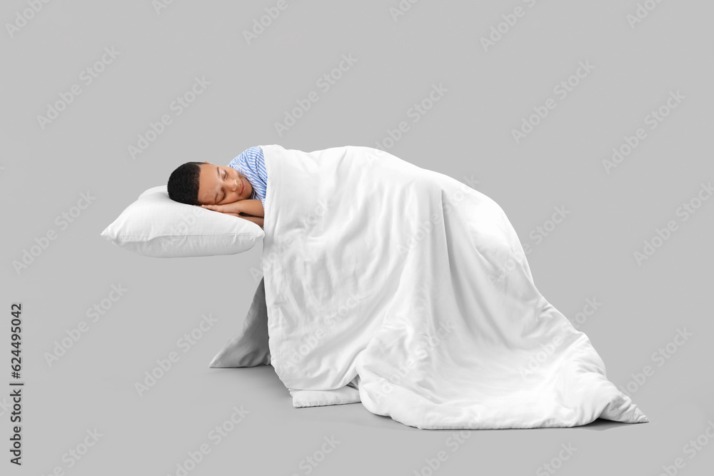 Little African-American boy with soft blanket sleeping on light background