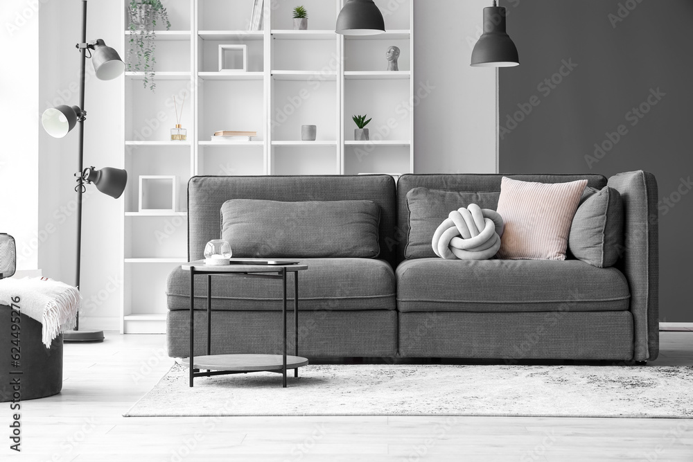 Interior of light living room with cozy grey sofa and coffee table