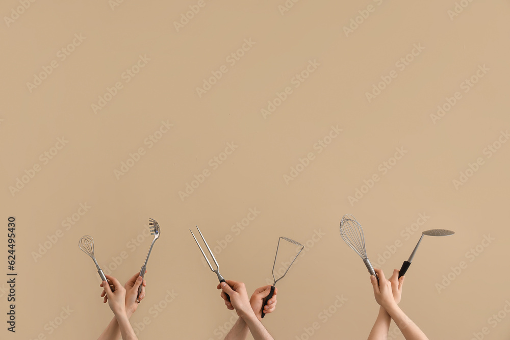 Female and male hands holding different kitchen utensils on brown background