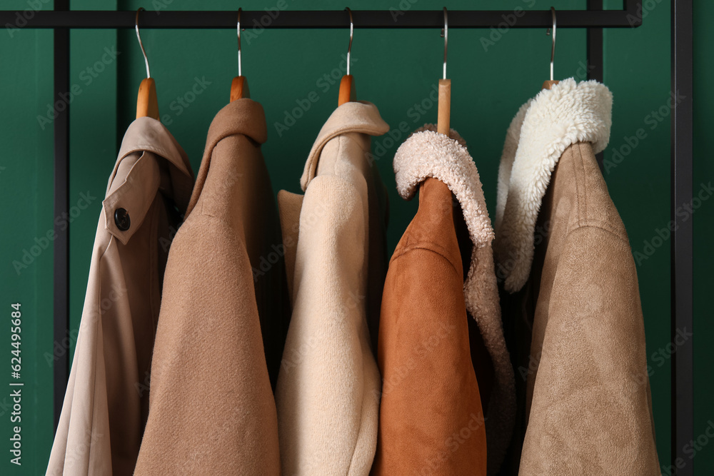 Stylish outwear hanging near green wall, closeup