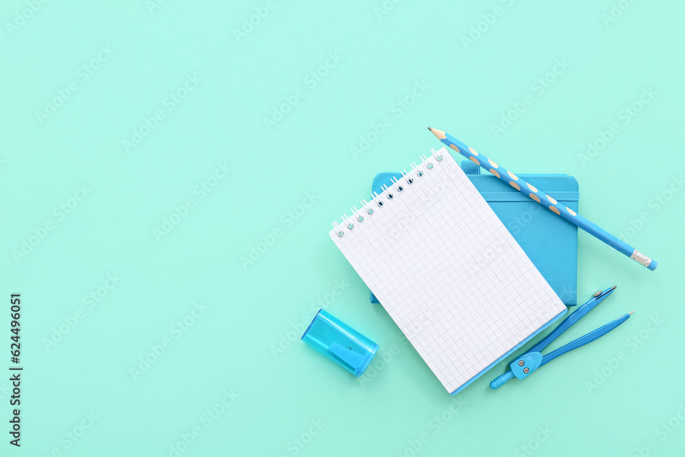 Blank notebook with different stationery on turquoise background