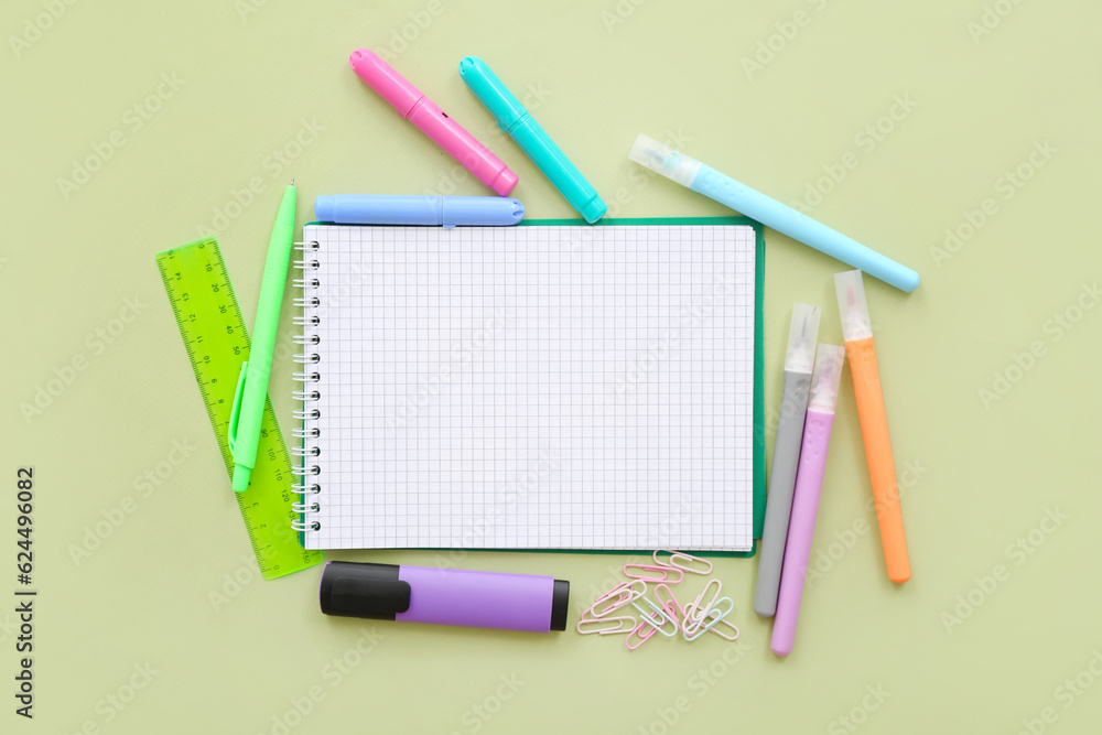 Blank notebook with different stationery on green background