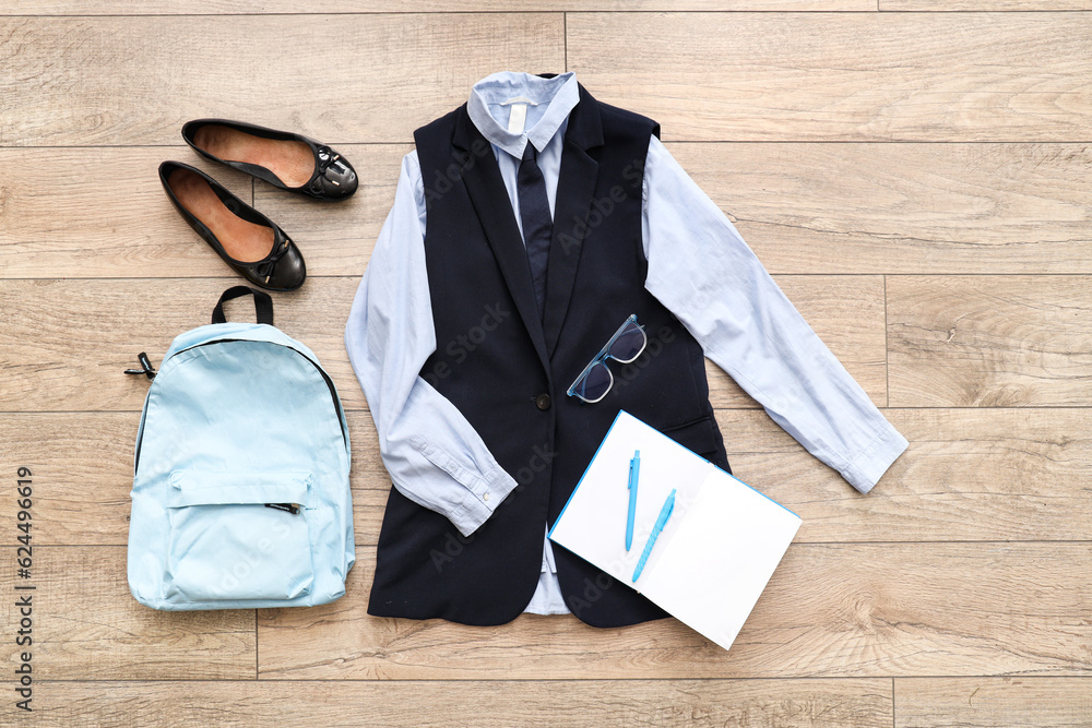 Composition with stylish school uniform, backpack, shoes, notebook and eyeglasses on wooden backgrou