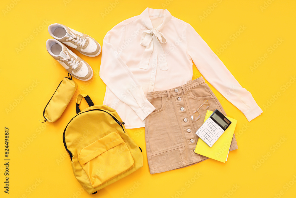 Composition with stylish school uniform, backpack, sneakers and stationery on orange background