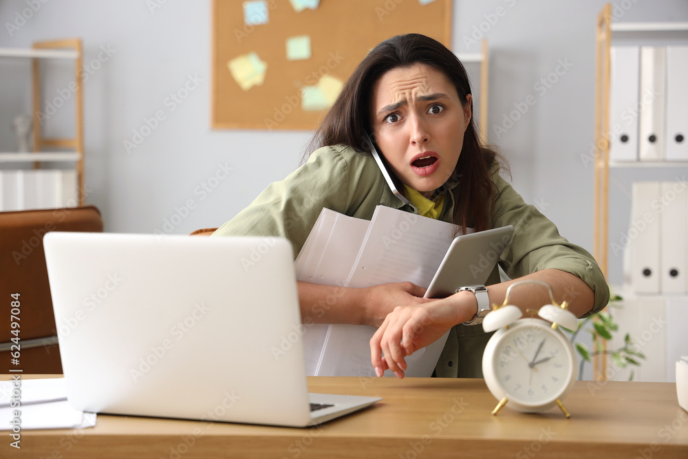 Stressed young businesswoman working under deadline in office