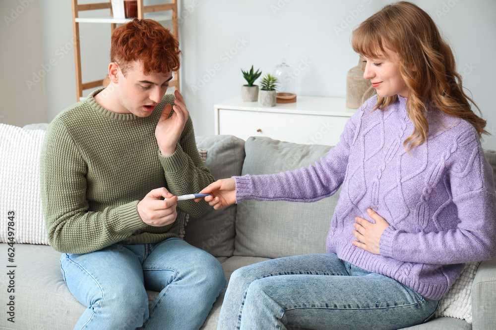 Young woman showing pregnancy test to her boyfriend at home